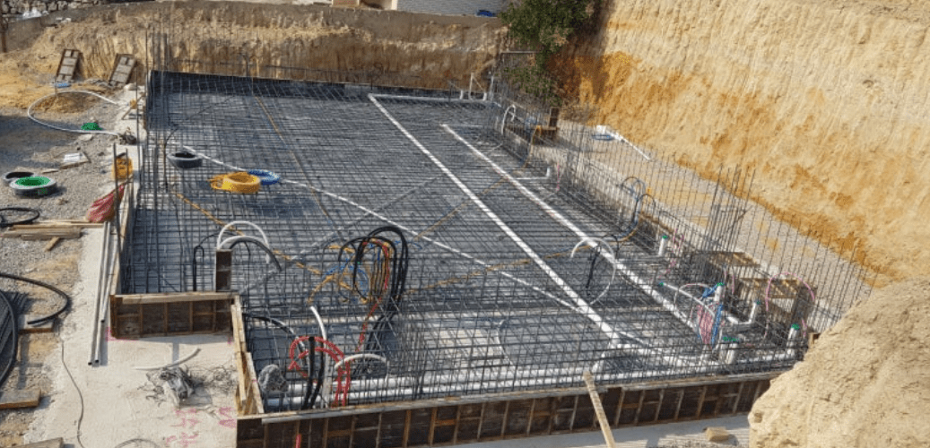 기초 공사를 위한 철근 구조물과 배관이 설치된 줄기초 현장 사진