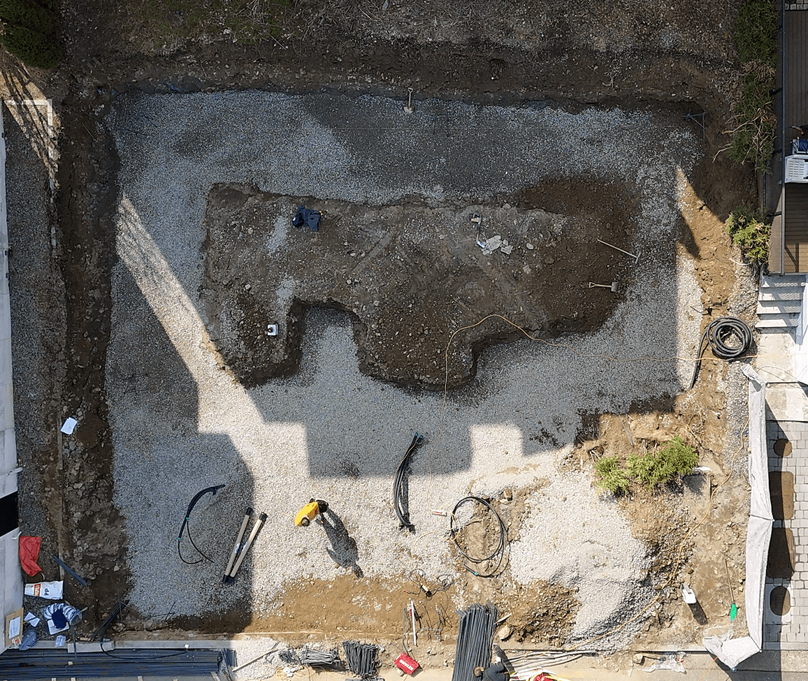 열린 건설 현장, 돌과 흙으로 채워진 기초 작업을 위한 부지 위에서 작업하는 인부들