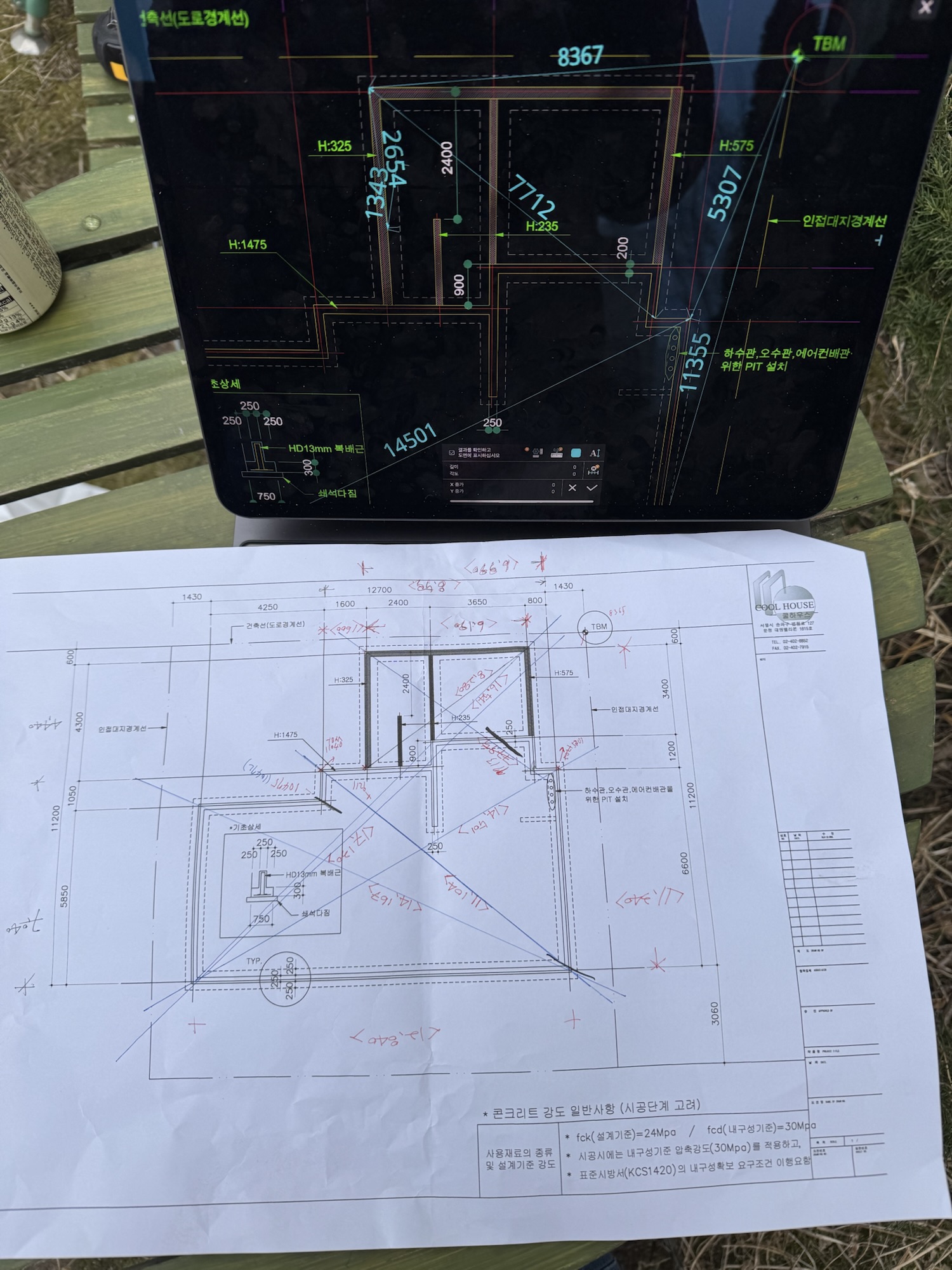 계획된 건축물의 도면과 측정값이 표시된 수첩과 종이가 놓여 있는 이미지.