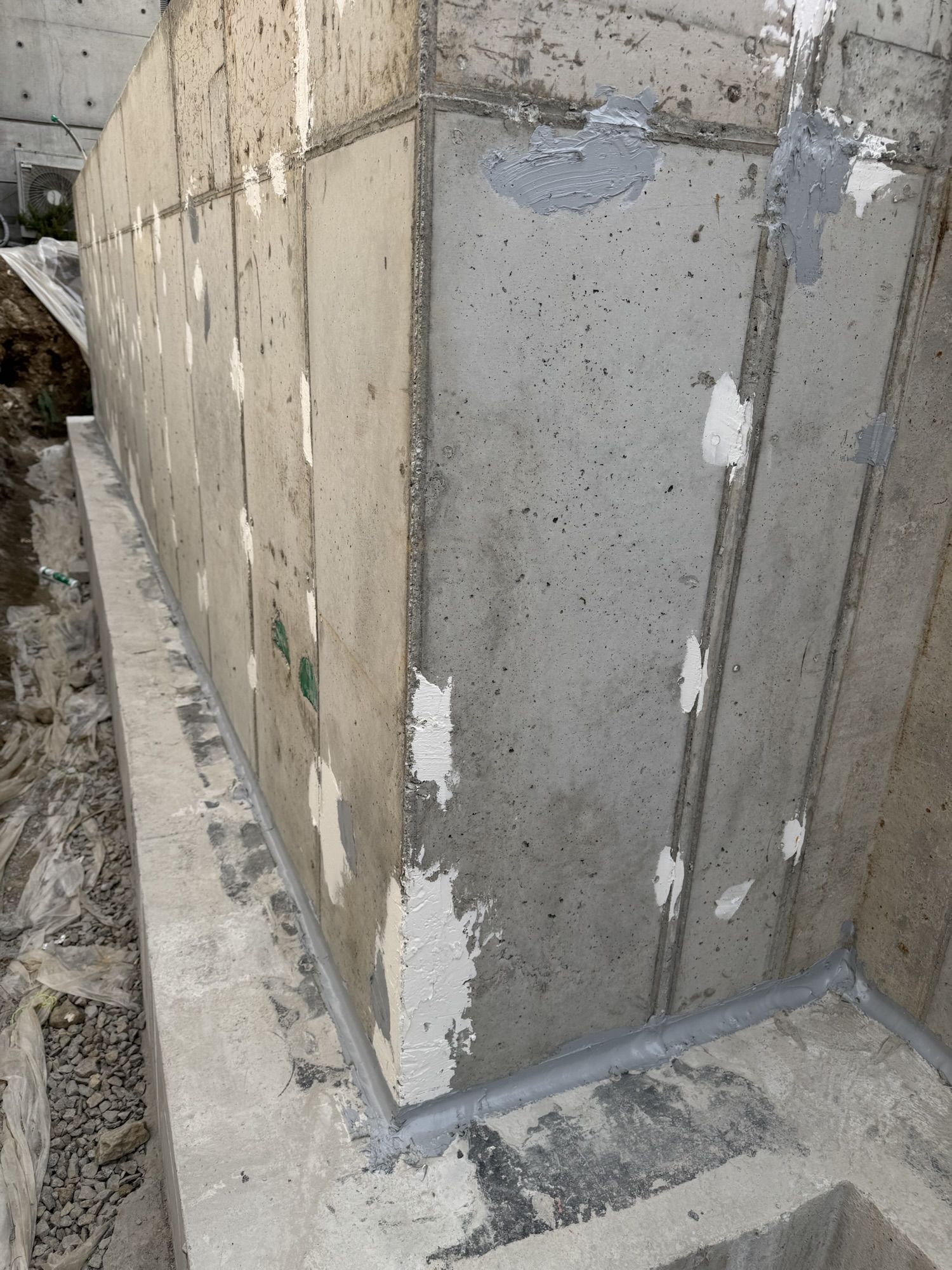 Concrete foundation wall with joint sealing material applied at the base, showcasing waterproofing preparations.