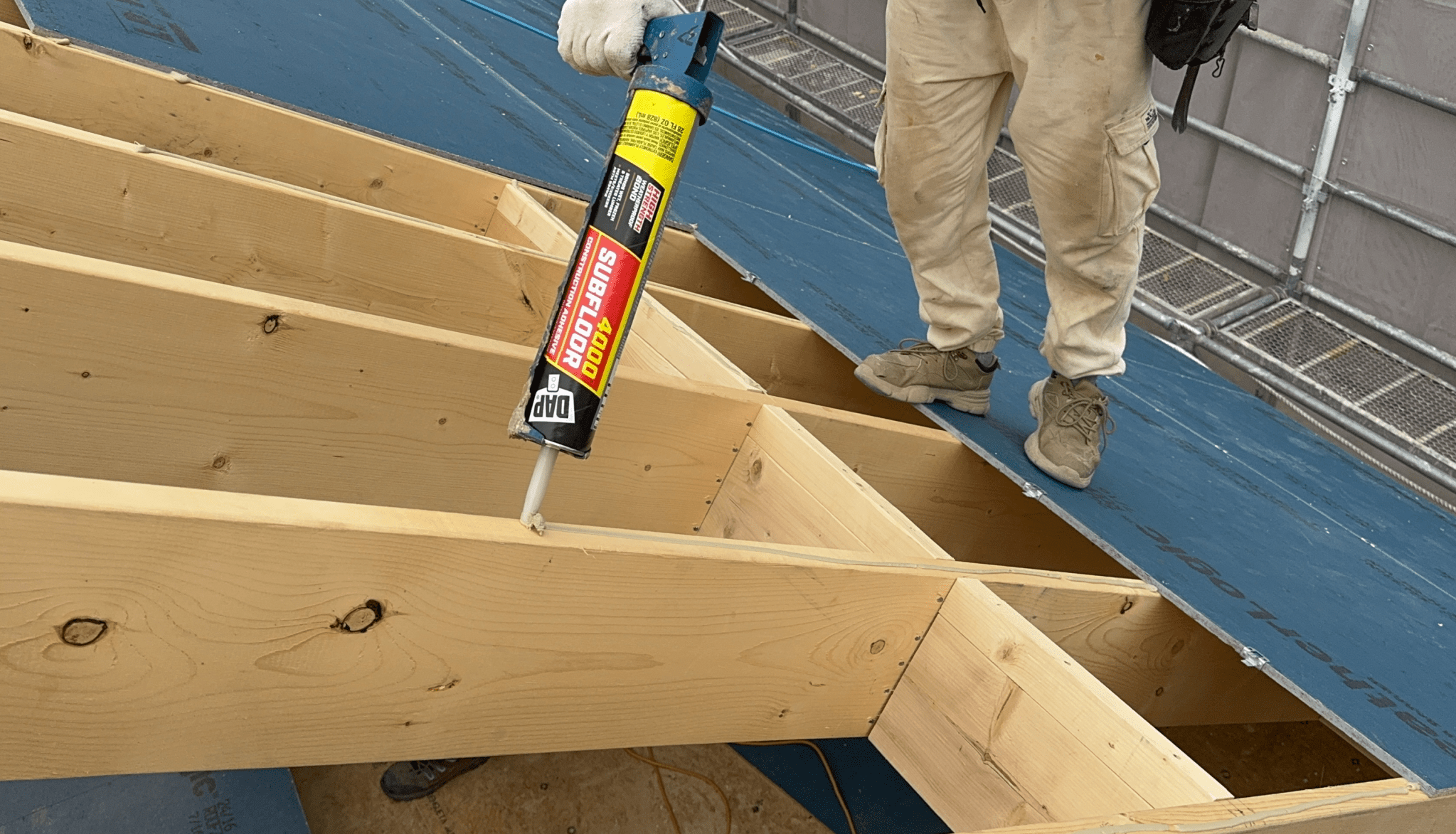 작업자가 나무 구조물에 접착제를 적용하고 있는 모습.