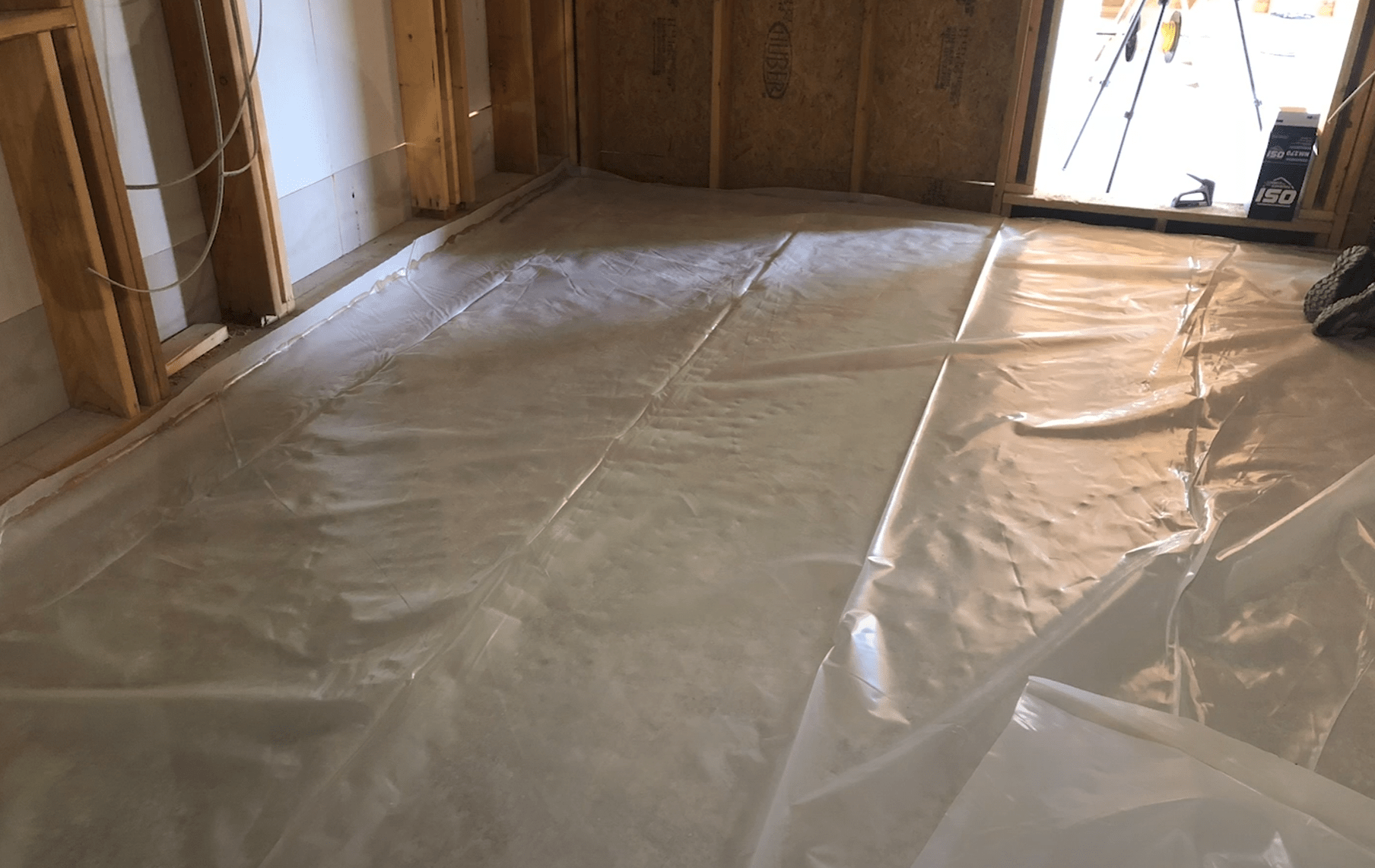 바닥에 투명 비닐이 깔려 있는 건축 현장 내부 모습.