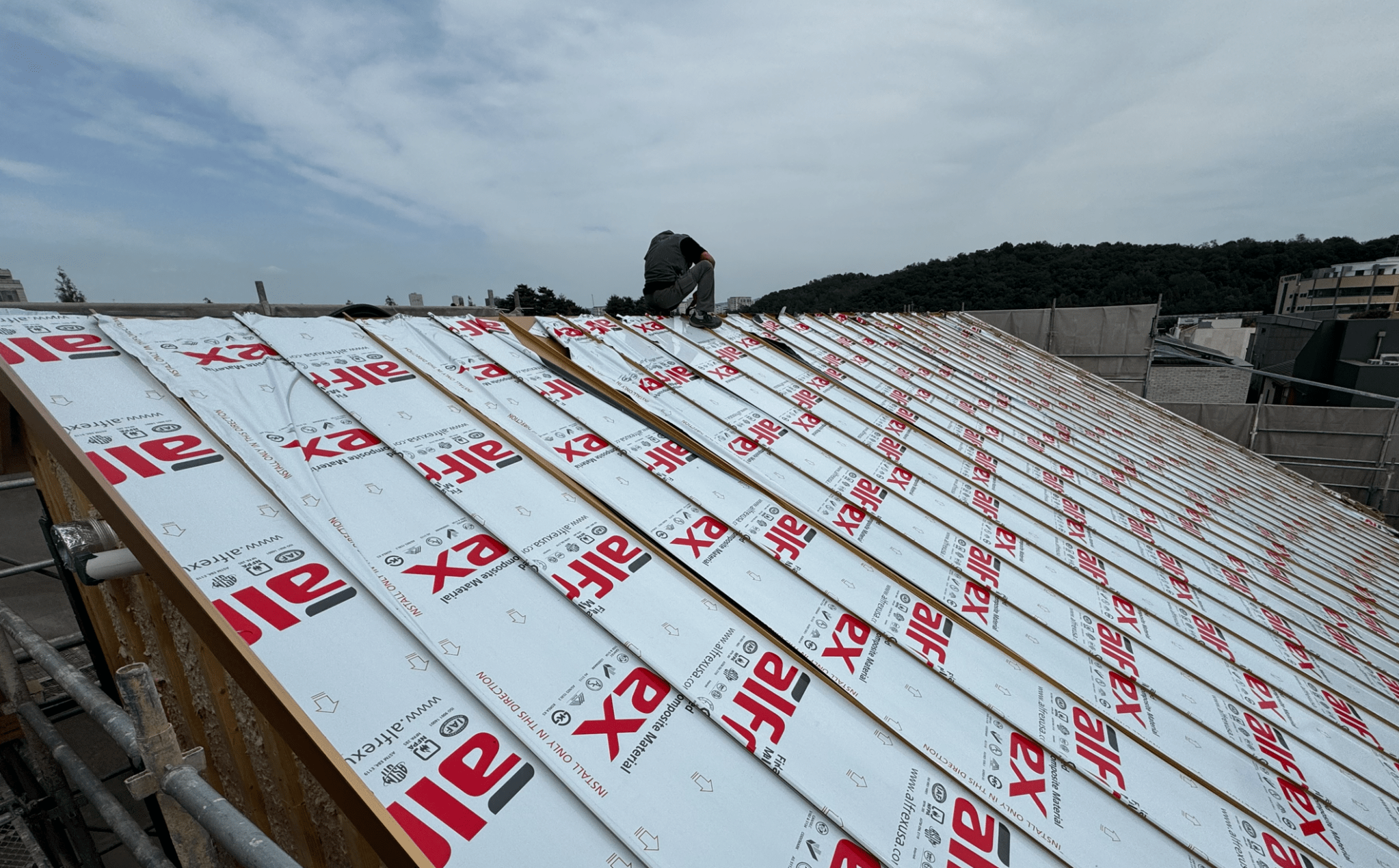 지붕 위에서 작업하고 있는 인부의 모습, 지붕 패널이 설치되고 있는 현장.
