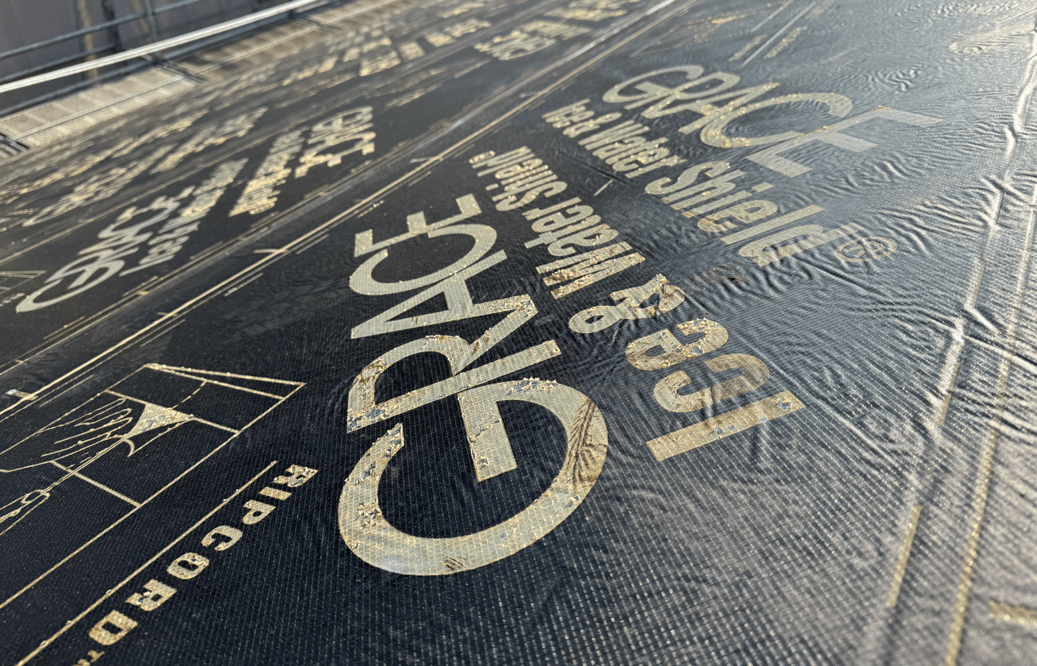 지붕에 설치된 Grace Ice and Water Shield 방수 시트의 다각도 모습으로, 텍스처와 인쇄된 문구가 선명하게 보인다.